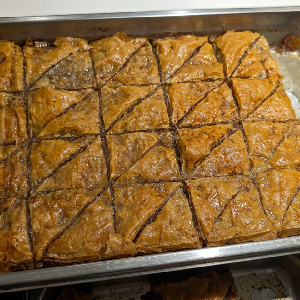 Golden, syrup-glazed baklava cut into triangular pieces in a large metal baking tray.